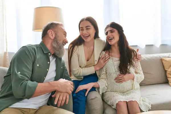 stock image cheerful father looking happily at his pregnant daughter and her cheerful partner, ivf concept