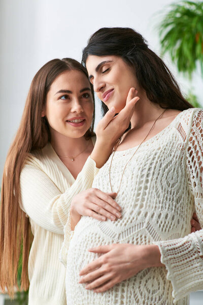 happy lgbt couple smiling cheerfully with hands on pregnant belly, hand to chin, ivf concept