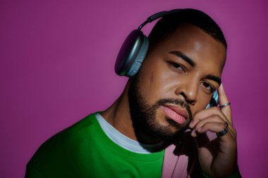good looking african american man posing with headphones looking at camera, fashion concept clipart