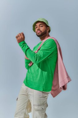 Omuzlarına kazak bağlanmış Afro-Amerikan genç bir adamın dinamik fotoğrafı, moda konsepti