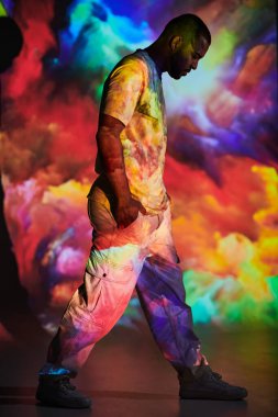 Profilde şık görünümlü bir adam renkli dijital projektör ışıkları ve moda konseptiyle yürüyor.