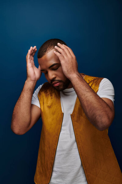 african american man in trendy vest gesturing and posing on dark blue background, fashion concept
