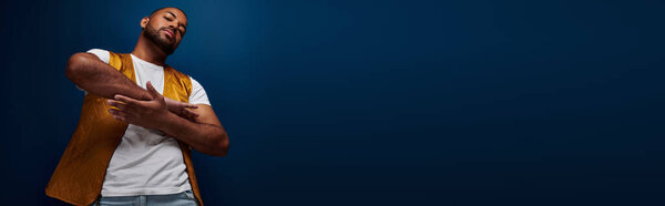 african american man in yellow vest slightly crossing his arms palm to palm, fashion concept, banner