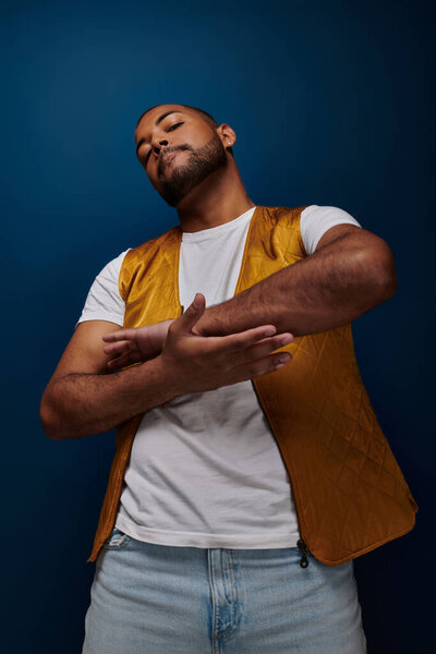 красивый молодой человек с серьгой скрещивая руки ладонью к ладони глядя в камеру, концепция моды