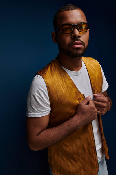 стильный молодой человек с бородой и солнцезащитными очками в желтой одежде, смотрящий в камеру, концепция моды