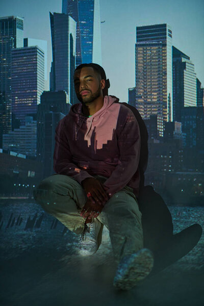 good looking man in trendy pink hoodie squatting in digital projector lights, fashion concept