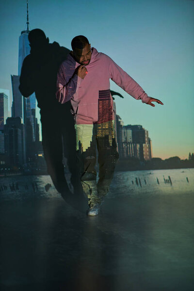 красивый молодой человек в розовой толстовке с оранжевым кольцом в цифровом проекторе огней, концепция моды