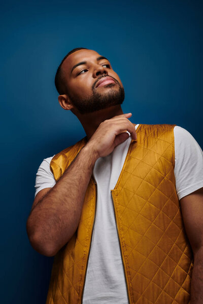 красивый мужчина в стильном желтом жилете, держась за руку рядом с лицом, концепция моды