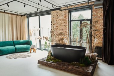 black bathtub inside of modern apartment with blue velour sofa, panoramic windows and plants clipart