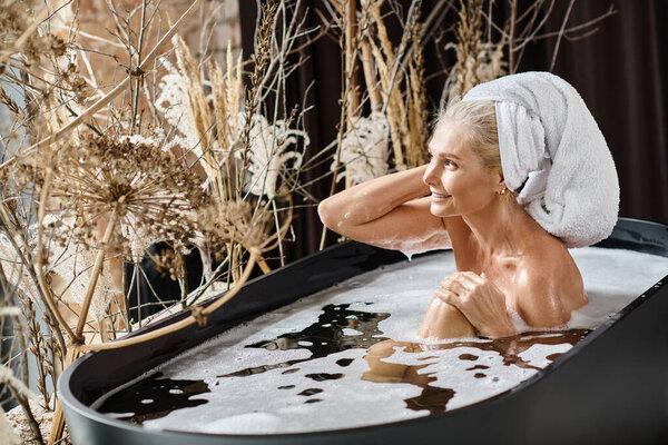 relaxed middle aged woman with white towel on head taking bath in modern apartment, beauty routine