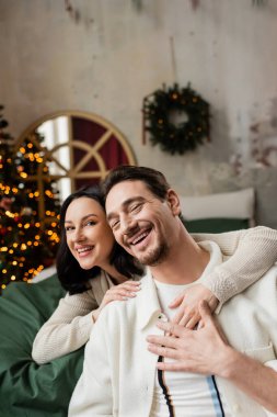 Kutsal Noel, mutlu kadın kocasını kucaklıyor ve modern yatak odasında birlikte vakit geçiriyor.