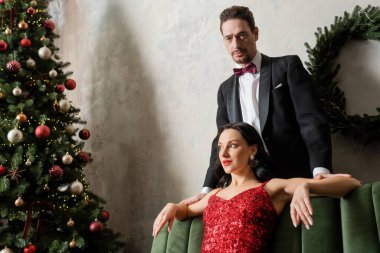 man in tuxedo standing behind beautiful woman in red dress near Christmas tree, wealthy people clipart
