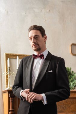 Noel arifesinde piyano başında papyonlu, resmi giyinmiş varlıklı bir beyefendi.