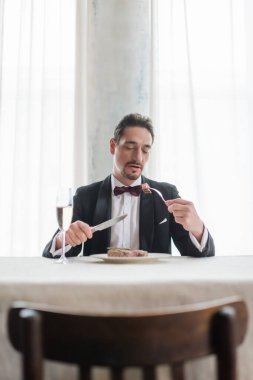 well-dressed gentleman in tuxedo eating delicious beef steak near glass of champagne, wealthy life clipart