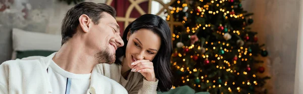 喜びの季節 現代の寝室で装飾されたクリスマスツリーの近くで妻とチャット幸せな男 バナー — ストック写真