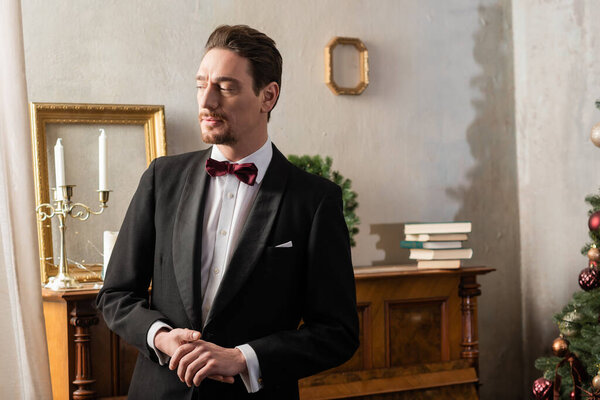 wealthy man in formal attire with bow tie standing near piano on Christmas eve, winter holidays