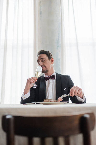 well-dressed gentleman in tuxedo enjoying taste of champagne while eating beef steak, wealthy life