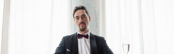 богатый и уверенный в себе джентльмен в смокинге с галстуком-бабочкой глядя в камеру, богатый стиль жизни баннер