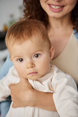 portrait of little toddler girl in hands of caring and smiling mother at home, blissful childhood clipart