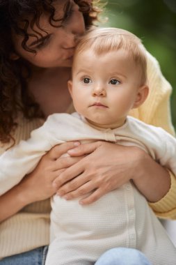 Sevgi dolu anne kucaklar ve küçük kızın başını öperek dışarı bakar, anne saadeti