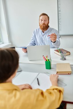 Masasında oturan bir adam, laptopuna dalmış, odaklanmış ve üretken..