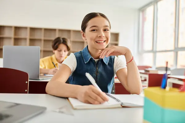 stock image A young girl sits at a desk, deeply engrossed in her notebook