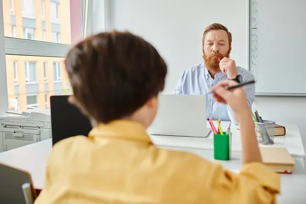 Stock image A man serenely sits at his desk, the glow of the computer screen and looking at boy