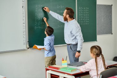 Dinamik bir erkek öğretmen, canlı bir sınıf ortamında bir grup çocuğa bilgi verir..