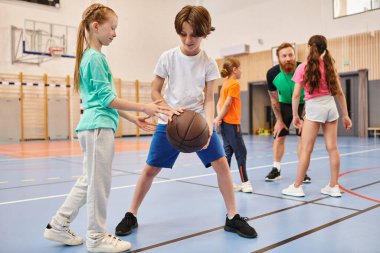 Coşkulu ve enerjik bir ortamda basketbol oynayan bir grup genç çocuk..