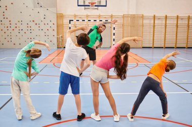 Çeşitli insanlar heyecanlı bir şekilde basketbol sahasında bir araya gelip etraflarındaki parlak enerjinin tadını çıkarıyorlar..