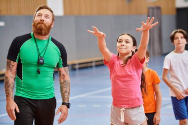 Çocuklar ve öğretmenler okulda basketbol oynuyorlar.