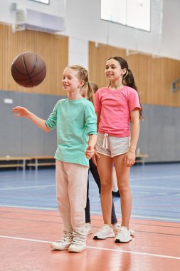 Kızlar bir basketbol sahasının tepesinde, erkek öğretmenlerinin talimatlarını dikkatle dinlerler..