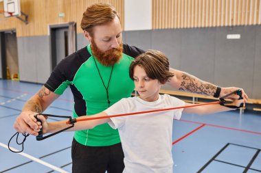 A man teaches a boy in a vibrant gym clipart