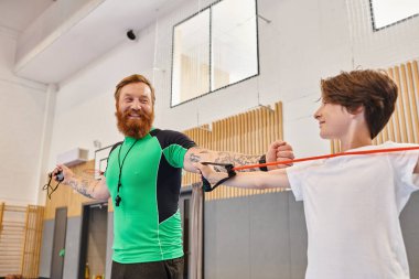 A jubilant teacher guides a young student through an exercise, in a vibrant learning space. clipart