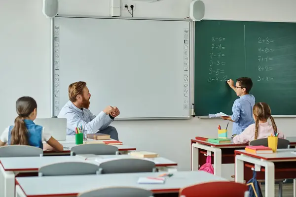 Group Children Sits Attentively Desks Front Blackboard Listening Male Teacher — Stock Photo, Image