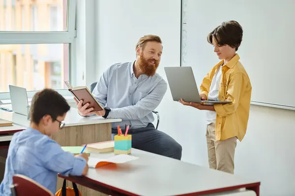 一个男人坐在办公桌前 专心致志地盯着面前的笔记本电脑屏幕 旁边是孩子们 — 图库照片