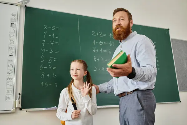 stock image A man in casual clothing stands beside a little girl, both looking attentively at a blackboard full of equations and diagrams.