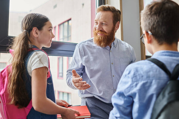 A bearded man is energetically teaching a diverse group of people in a bright, lively classroom setting.