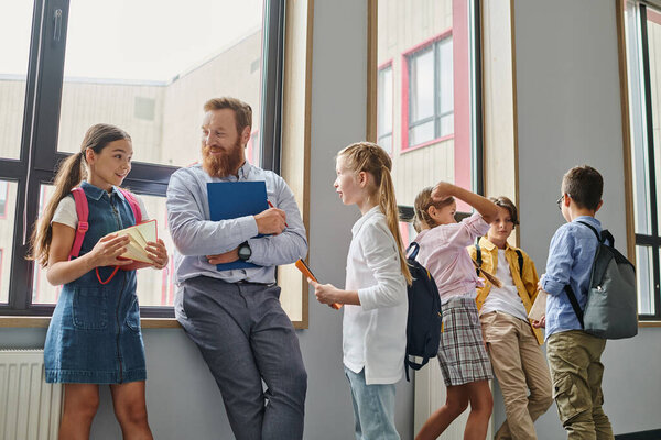 Группа молодых людей, стоящих в единстве, слушая своего учителя-мужчину в яркой, живой обстановке класса.