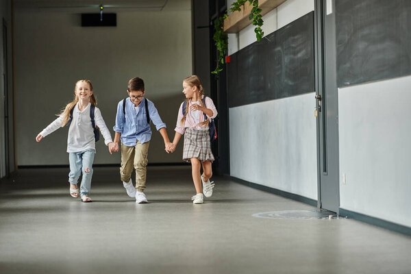 A group of children, walking down a brightly lit hallway in a school.