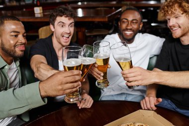 four excited multicultural friends clinking with glasses of beer in bar, men on bachelor party clipart