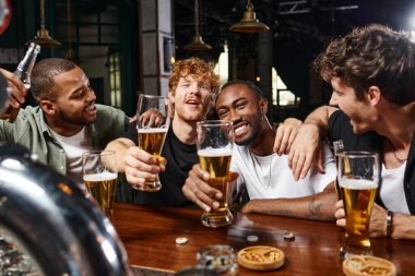 Bekarlığa veda partisinde elinde bira bardakları olan dört mutlu etnik erkek, barda erkek arkadaşlar.