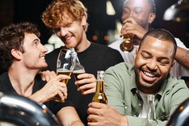 Mutlu ve sarhoş Afrikalı Amerikalı adam diş telleri ile bardaki erkek arkadaşlarının yanında gülümsüyor, bekarlığa veda partisi