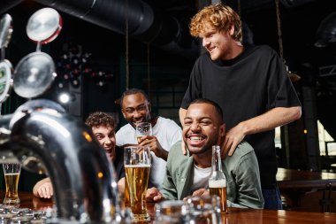 man touching shoulders of happy african american groom during bachelor party, male friendship clipart