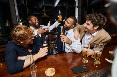 Bir grup ırklar arası mutlu iş arkadaşı barda bira içiyor, işten sonra eğleniyorlar.