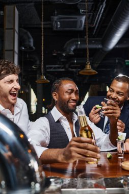 Mutlu ve sarhoş ırklar arası arkadaşlar işten sonra barda tekila ve bira içiyorlar, erkek arkadaşlığı.