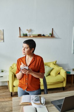 vertical shot of young attractive woman taking notes slightly smiling and looking away, studying clipart