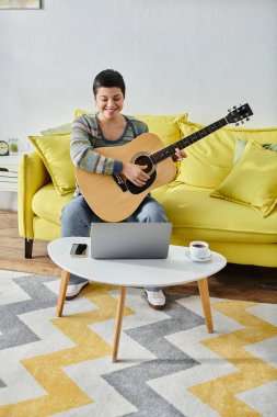 Uzak bir müzik dersinde gitar çalmayı öğrenen genç bir kadının dikey çekimi, evde eğitim.