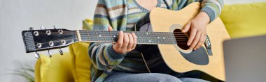 Uzaktan kumandalı sınıfta gitar çalmayı öğrenen bir kadının dizüstü bilgisayarın önünde oturduğu görüntüler.