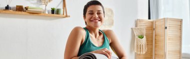 Spor giyinen neşeli kadın kameraya gülümsüyor ellerinde spor paspası, spor ve spor, afiş